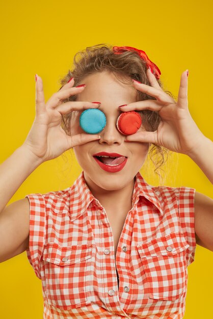 Portrait de jolie femme couvrant ses yeux avec des macarons