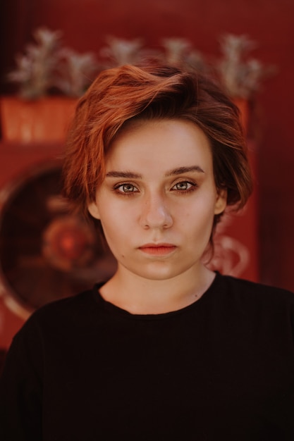 Portrait de jolie femme effrontée avec de courts cheveux rouges à l'arrière-cour dans la vieille ville aux murs rouges