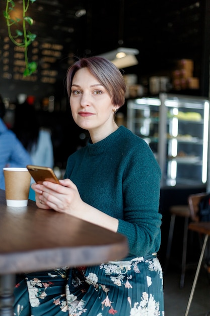 Portrait d'une jolie femme élégante et élégante assise dans un café