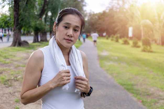 Portrait jolie femme en forme de sourire avec une serviette blanche au repos après des exercices de sport d'entraînement à l'extérieur