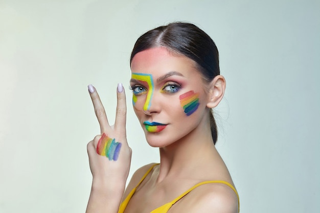 Portrait d'une jolie femme avec un maquillage lumineux avec drapeau arc-en-ciel LGTB