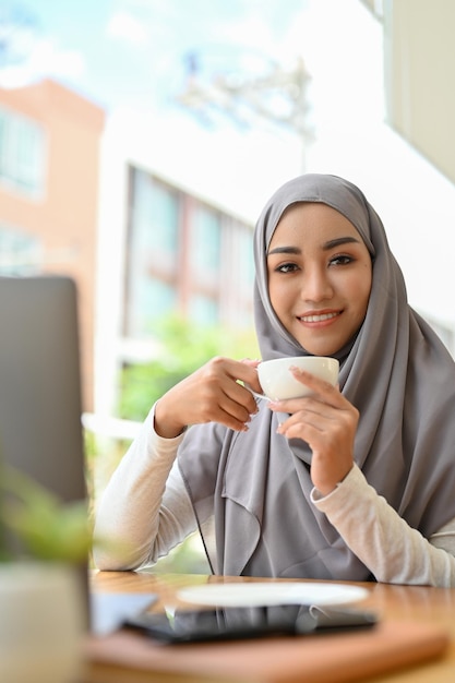 Portrait d'une jolie femme musulmane asiatique ou d'une femme d'affaires en sirotant un café le matin