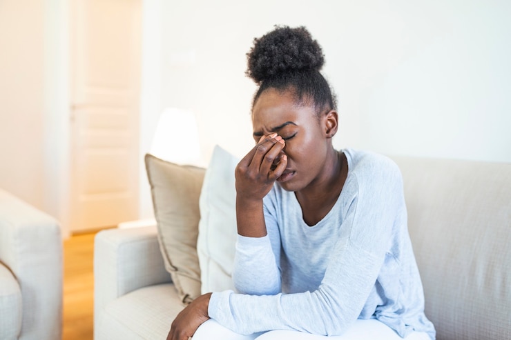 Photo portrait d'une jolie femme noire assise sur un canapé à la maison avec un mal de tête