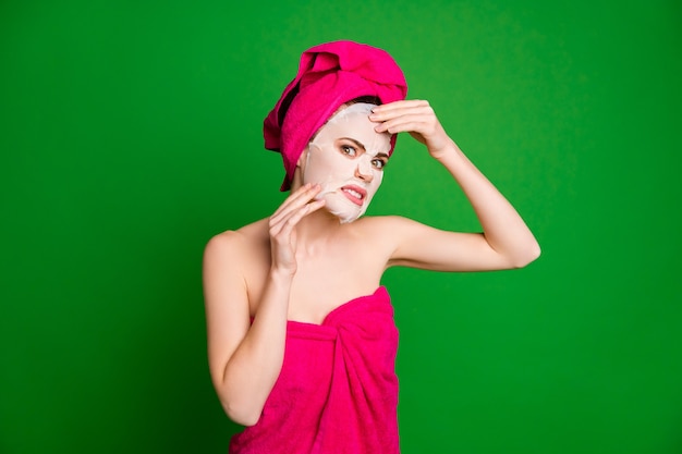 Portrait de jolie femme nue nue irritée portant un turban appliquant un masque facial grimaçant isolé sur fond de couleur vert clair