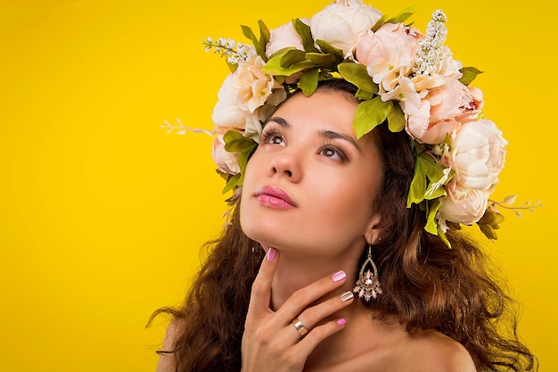 Portrait d'une jolie femme portant une couronne sur mur jaune