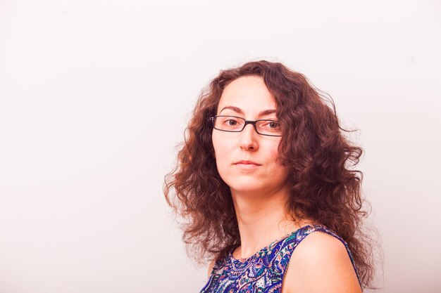 Portrait d'une jolie femme sérieuse portant des lunettes sur un mur gris, avec espace de copie