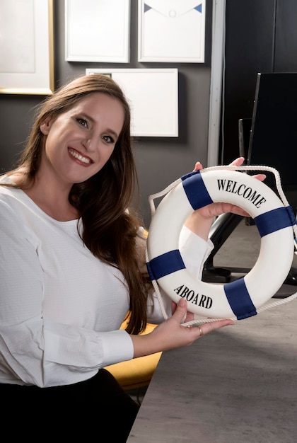 Portrait d'une jolie femme souriante caucasienne et étreignant une bouée de sauvetage Mains de femmes avec une petite bouée de sauvetage Ouvriers d'affaires assis au bureau