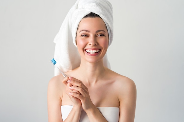 Portrait de jolie femme souriante caucasienne isolée sur un mur blanc tourné en se brossant les dents.