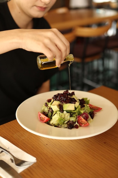 Portrait d'une jolie femme souriante caucasienne mangeant de la salade se concentrant sur la main et la fourchette