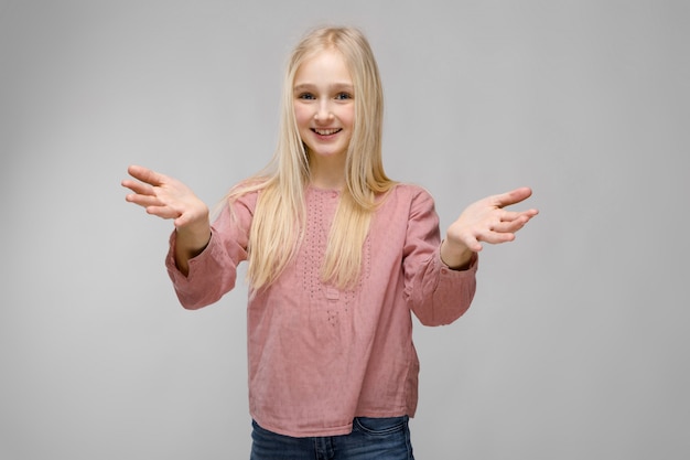 Portrait de jolie fille d'adolescent blonde adorable souriante et souriante dans des verres en chemisier rose à bras ouverts