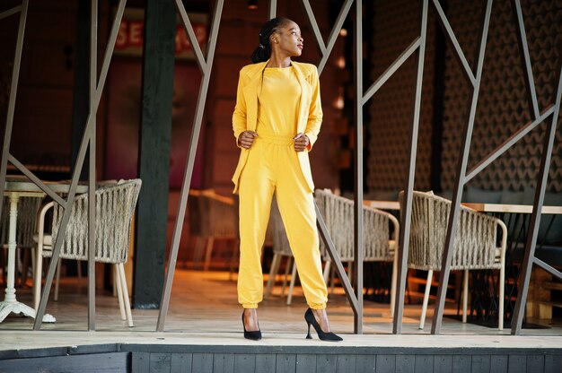 Portrait d'une jolie fille afro-américaine gaie et gaie à la mode et attrayante qui porte une veste ou un costume de couleur jaune vif et brillant.