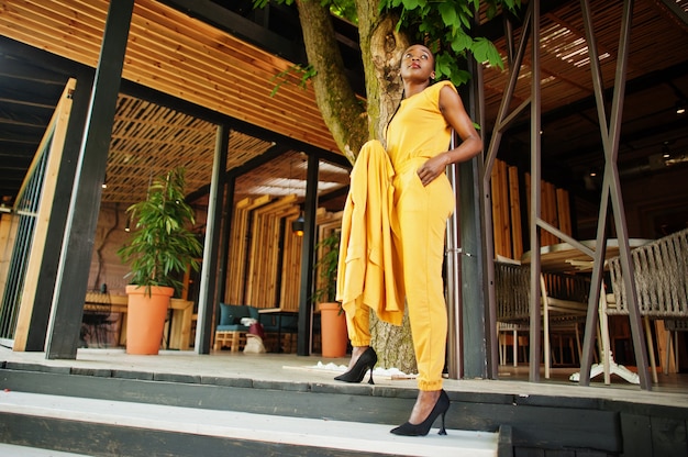 Portrait d'une jolie fille afro-américaine gaie et gaie à la mode et attrayante qui porte une veste ou un costume de couleur jaune vif et brillant.