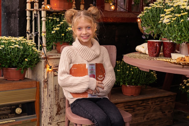 portrait d'une jolie fille en automne dans le jardin avec un livre et des fleurs