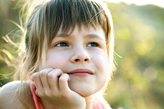 Portrait d'une jolie fille aux yeux gris et aux longs cheveux blonds s'appuyant sur ses mains