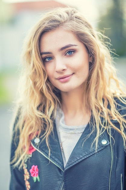 Portrait de jolie fille blonde aux cheveux longs bouclés et aux yeux bleus.