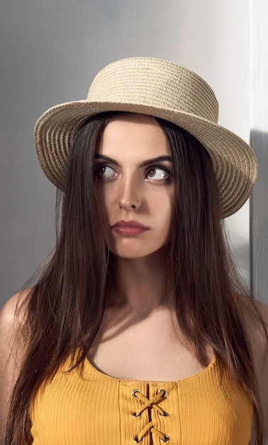 Portrait de jolie fille bouleversée portant un chapeau de paille et levant les yeux en pensant