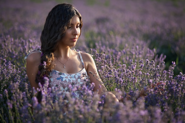 Portrait de jolie fille brune dans le champ de lavande. Modèle de lavande d'été posant devant la caméra.