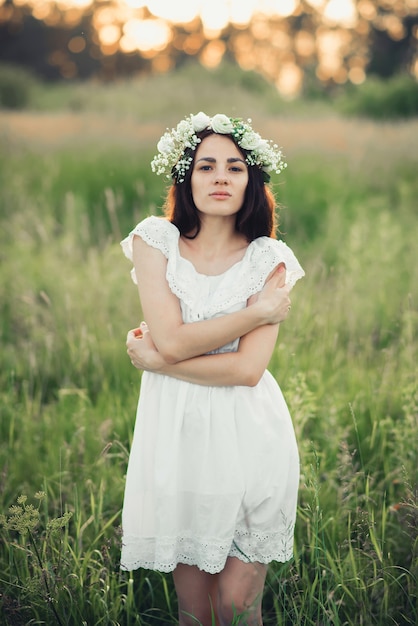 Portrait de jolie fille brune en robe blanche et avec couronne florale