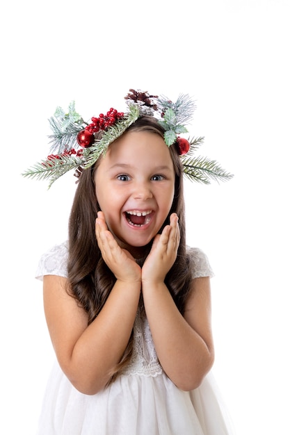 Portrait d'une jolie fille charmante avec la bouche ouverte dans une couronne de Noël surprise et impatiente de ...