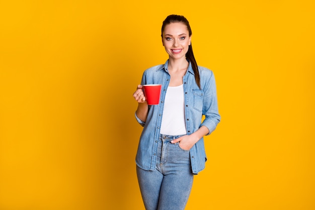 Portrait de jolie fille cool tenir une tasse avec un café au lait chaud profiter d'une pause de temps libre porter des vêtements de style décontracté isolés sur un fond de couleur brillant