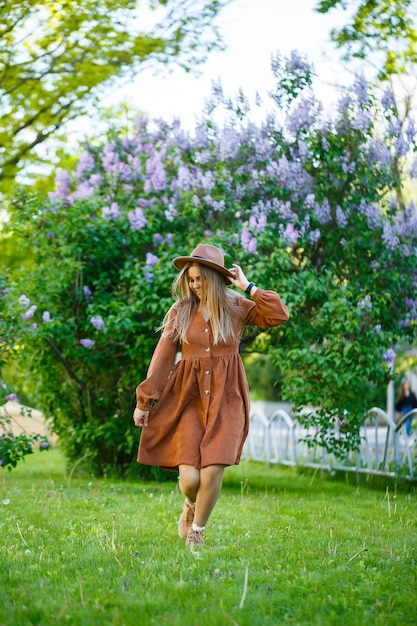 Portrait d'une jolie fille dans un chapeau marron avec un lilas dans le jardin