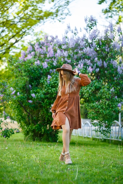 Portrait d'une jolie fille dans un chapeau marron avec un lilas dans le jardin