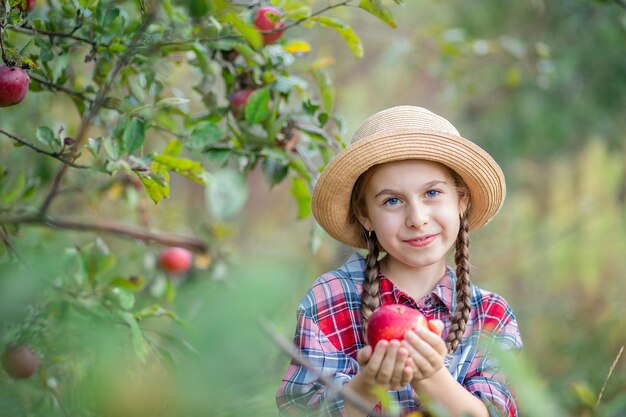 Portrait d'une jolie fille dans un jardin de ferme avec une pomme rouge Récolte d'automne de pommes