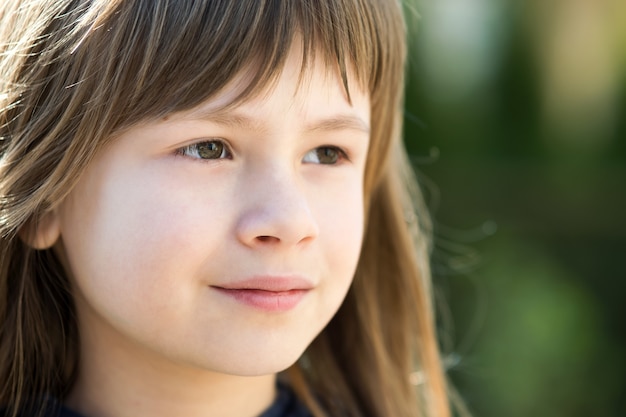 Portrait de jolie fille enfant aux yeux gris et longs cheveux blonds à l'extérieur. Enfant de sexe féminin mignon sur une chaude journée d'été à l'extérieur.