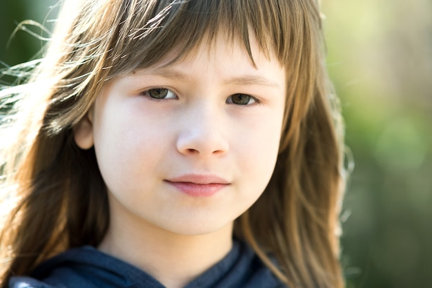 Portrait de jolie fille enfant aux yeux gris et longs cheveux blonds à l'extérieur sur fond clair flou. Enfant de sexe féminin mignon sur une chaude journée d'été à l'extérieur.