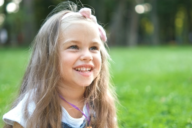 Portrait de jolie fille enfant dans le parc d'été souriant joyeusement.