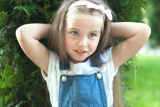Portrait de jolie fille enfant debout à l'extérieur dans le parc d'été souriant joyeusement.