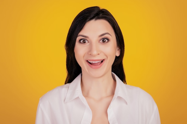 Portrait d'une jolie fille excitée face à la caméra sur fond jaune