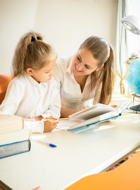 Portrait de jolie fille à faire ses devoirs avec sa mère