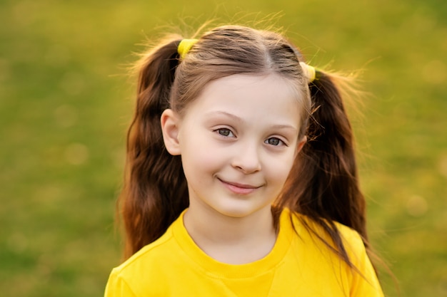 Portrait d'une jolie fille heureuse 7-8 ans dans la nature dans le parc d'été.