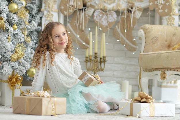 Portrait de jolie fille heureuse assise avec des cadeaux de Noël