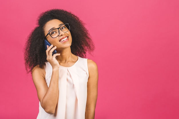 Portrait d'une jolie fille heureuse en conversation décontractée sur téléphone mobile et riant de rose.