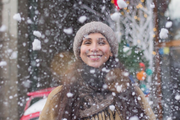 Portrait d'une jolie fille heureuse pendant les vacances de Noël lors d'une foire de Noël sous la neige