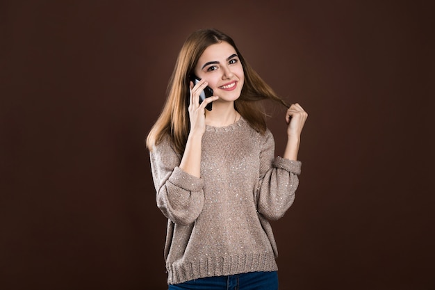 Portrait d'une jolie fille heureuse en pull parler sur téléphone mobile