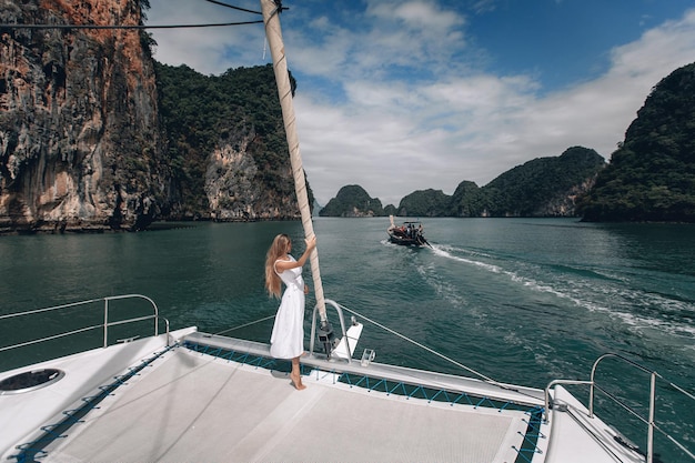 Portrait d'une jolie fille heureuse avec une robe blanche et de longs cheveux blonds bouclés debout sur un yacht en été. Phuket. Thaïlande