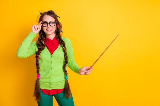 Portrait d'une jolie fille intelligente gaie et funky montrant l'espace de copie d'enseignement du sujet isolé sur fond de couleur jaune brillant