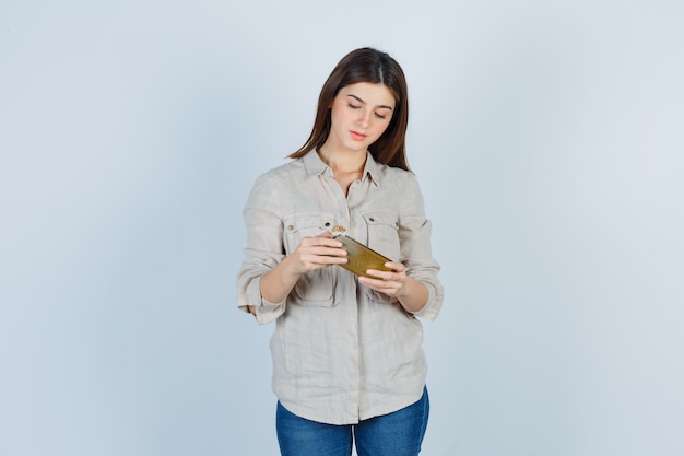 Portrait de jolie fille jouant au jeu par téléphone portable en chemise et à l'accent