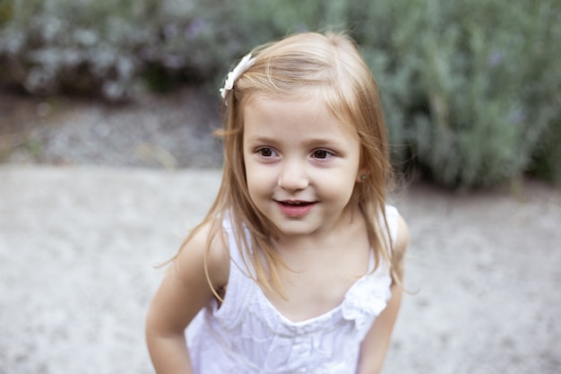 Portrait de jolie fille jouant dans le jardin fleuri ensoleillé