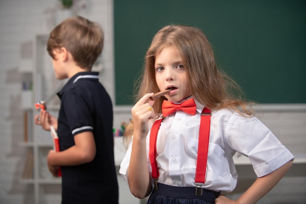 Portrait d'une jolie fille joyeuse mangeant des aliments sains ou mangeant des bonbons au chocolat en classe à l'école primaire