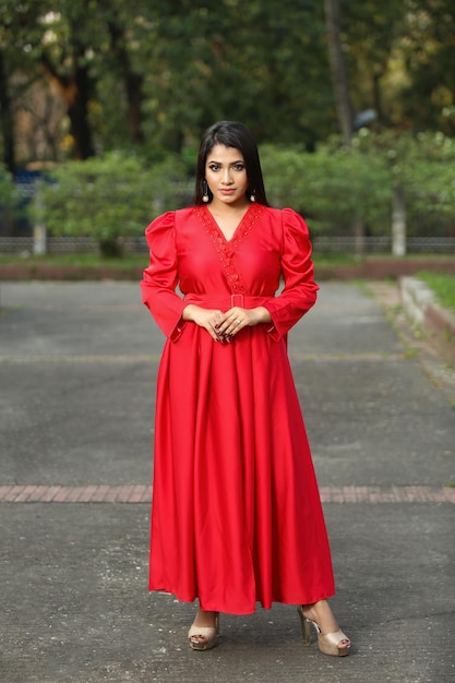 Portrait d'une jolie fille à la mode vêtue d'une robe longue rouge avec une pose élégante