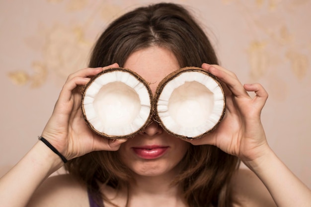 Portrait de jolie fille avec des noix de coco près de ses yeux.