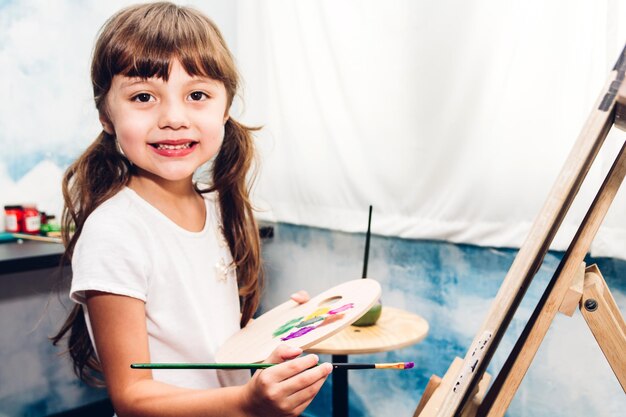 Photo portrait d'une jolie fille peignant une toile dans un studio d'art