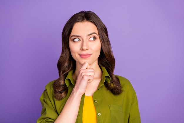 Portrait d'une jolie fille pleine d'esprit, toucher les mains du menton, regarder la surface, penser au plan des pensées pour les week-ends futurs, porter une tenue cool de style décontracté isolée sur un fond de couleur violette