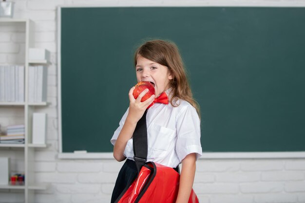 Portrait d'une jolie fille avec une pomme rouge dans la salle de classe