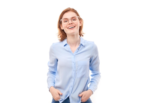 Portrait de jolie fille rousse en chemise d'affaires et lunettes souriant joyeusement isolé sur fond de studio blancxA