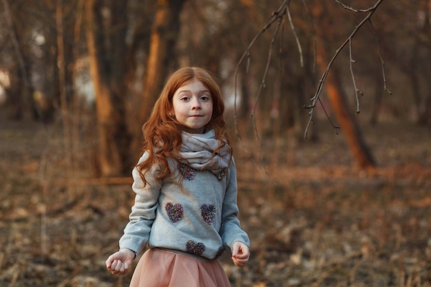 Portrait d'une jolie fille rousse avec des taches de rousseur debout dans un parc ou une forêt d'automne ou de printemps